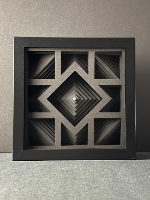 NF-02. Front view of the framed paper relief, with nested diamond layers and a pale cyan center.