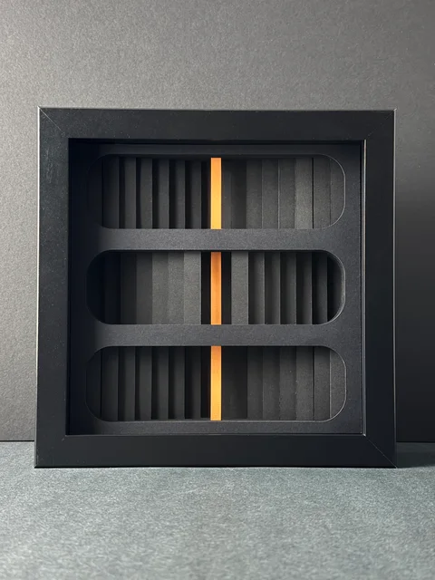 NF-03. Front view of the framed paper relief, with rounded openings and a vertical orange core.